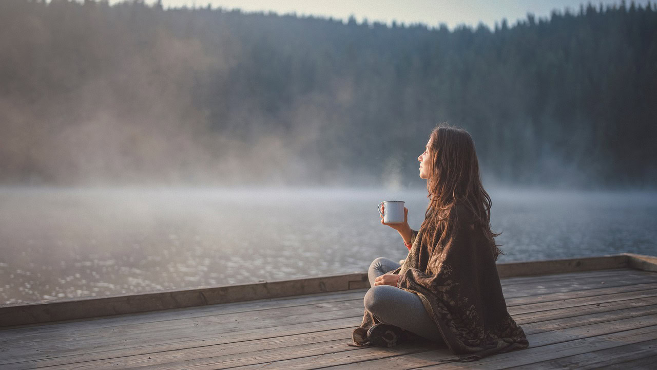 Frau am See mit Kaffeebecher