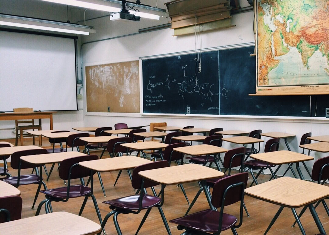 ein leeres Klassenzimmer mit Tischen, Stühlen, einer Tafel und einer Wandkarte